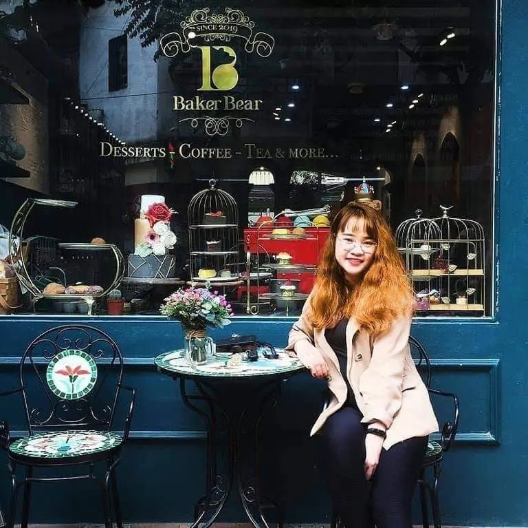Woman sitting outside a bakery cafe with desserts, pastries, and floral table decor